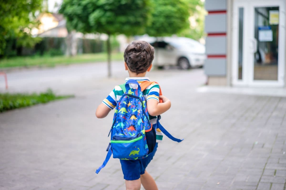 Criança indo à escola a pé com o dispositivo de localização na mochila